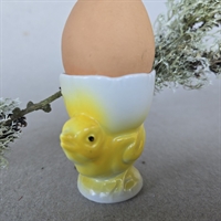 hvidt porcelæns æggebæger på fod med gul kylling gammel æggeholder